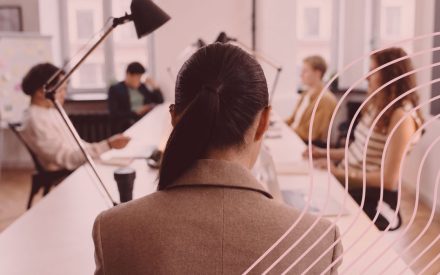 Personer sitter runt ett konferensbord i ett ljust kontorsrum