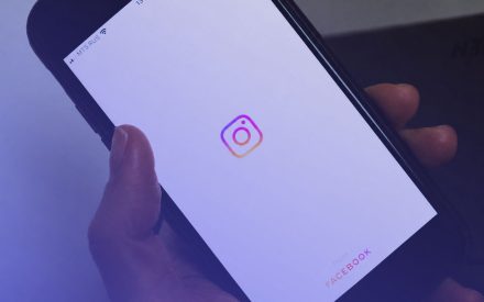 En hand håller i en smart phone, på skärmen kan man se instagram loggan.