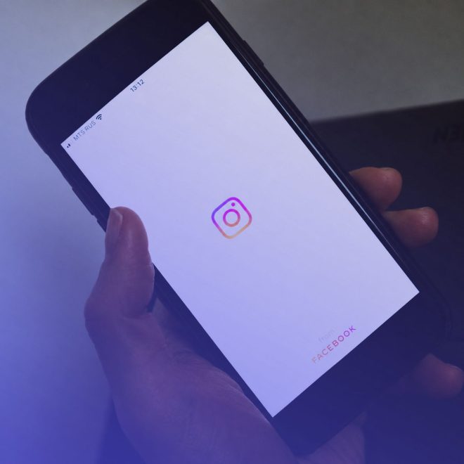 En hand håller i en smart phone, på skärmen kan man se instagram loggan.