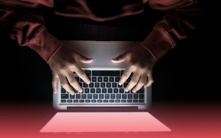 person framför dator i mörkt rum