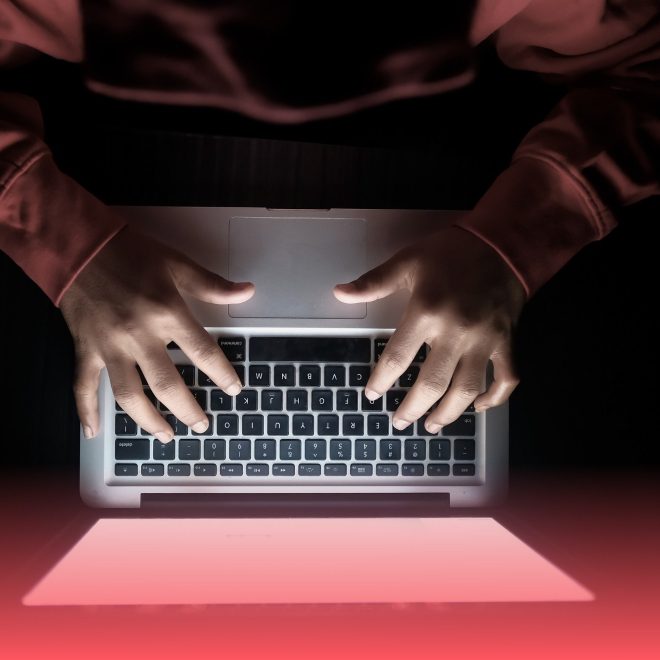person framför dator i mörkt rum