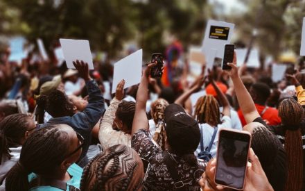 Människor protesterar med skyltar och filmar med sina mobiler.