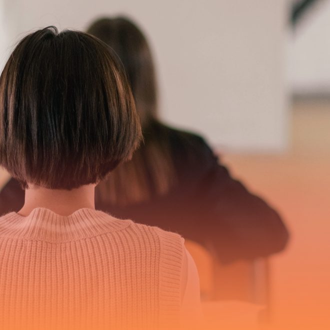Elever sitter med ryggen mot kameran i klassrum