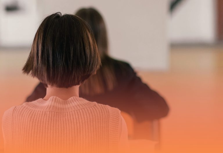 Elever sitter med ryggen mot kameran i klassrum