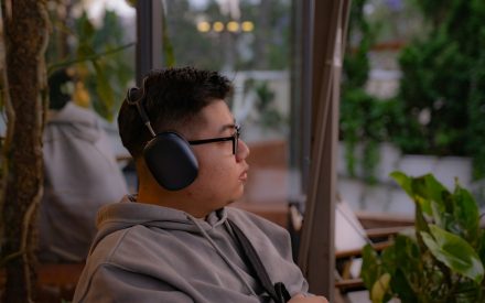 Man iklädd grå hoodtröja och svarta hörlurar.