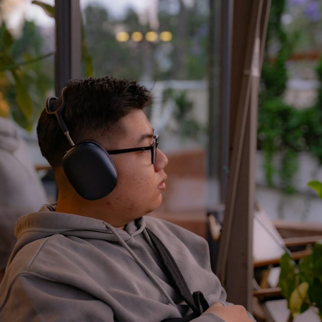 Man iklädd grå hoodtröja och svarta hörlurar.