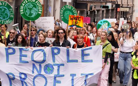 Klimatdemonstration. Människor går med banderollen People not profit.