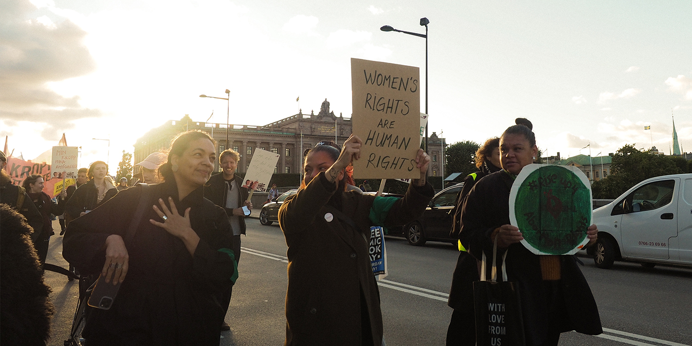 Demonstranter med protestskyltar utanför Sveriges riksdag.