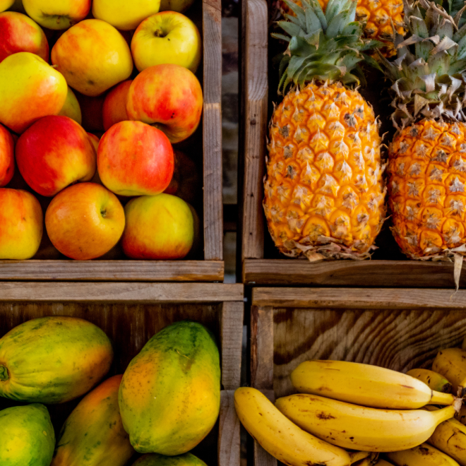 Äpplen, ananas, mango och bananer i lådor