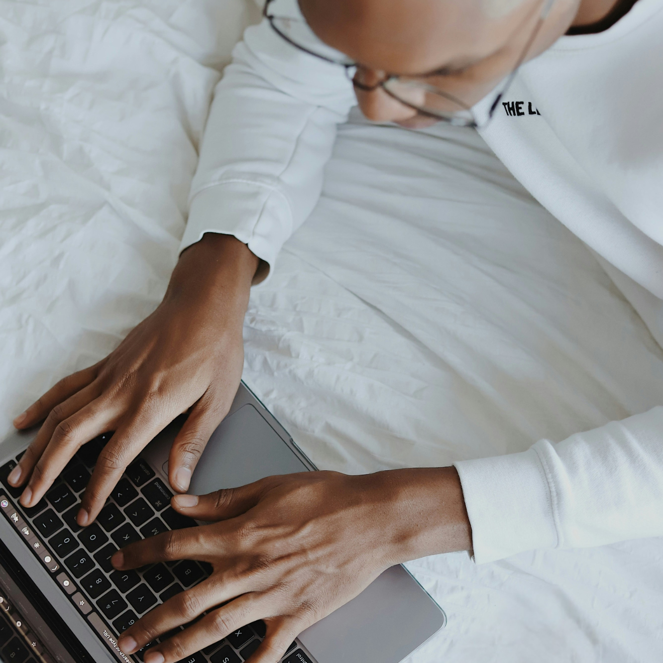 man ligger på en säng och skriver på dator