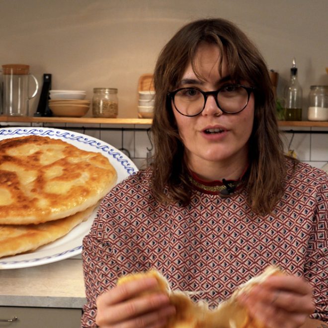 Amanda står i ett kök och håller i ett placinta bröd