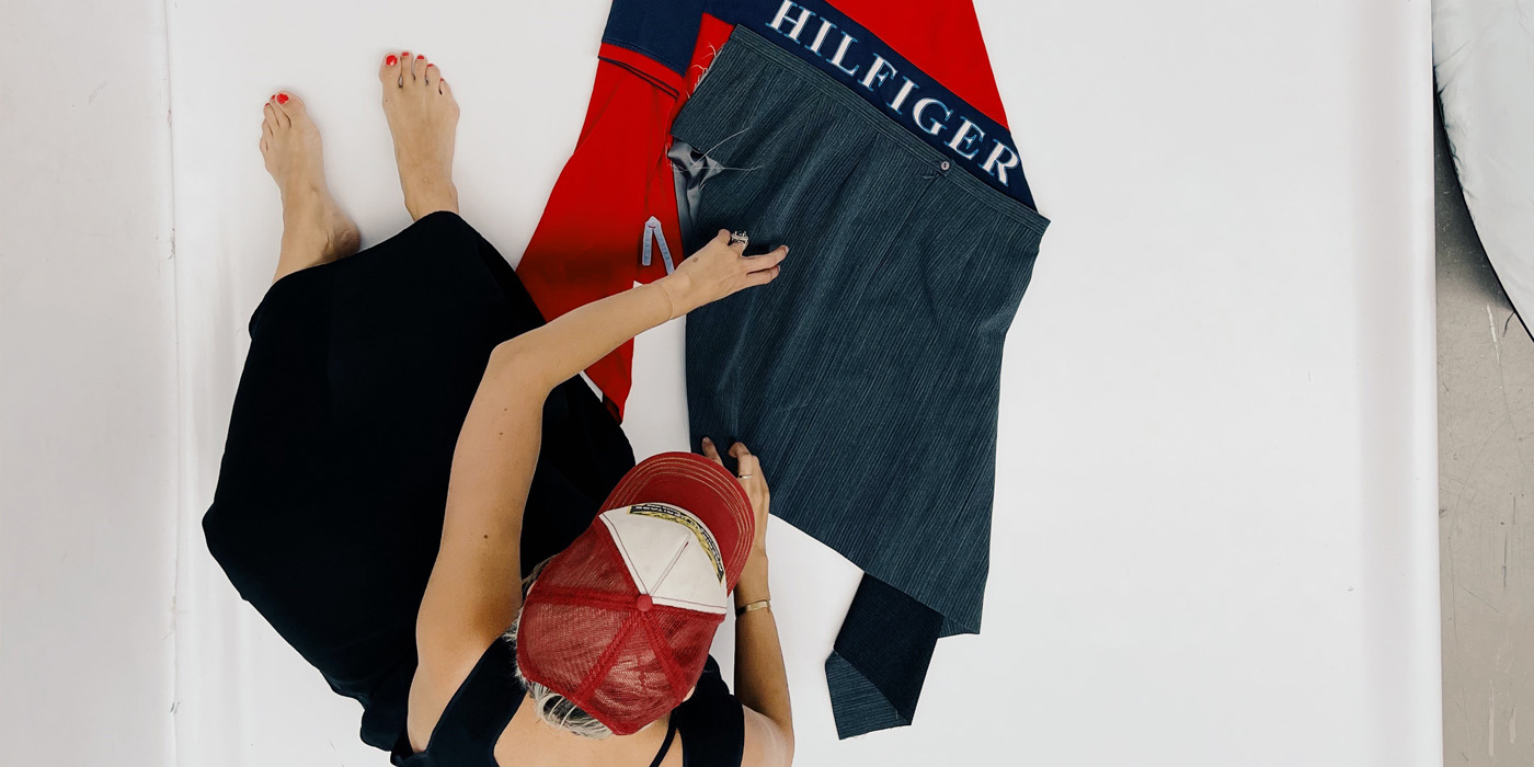 Anna sitter på golvet iklädd keps och jobbar med några tyger