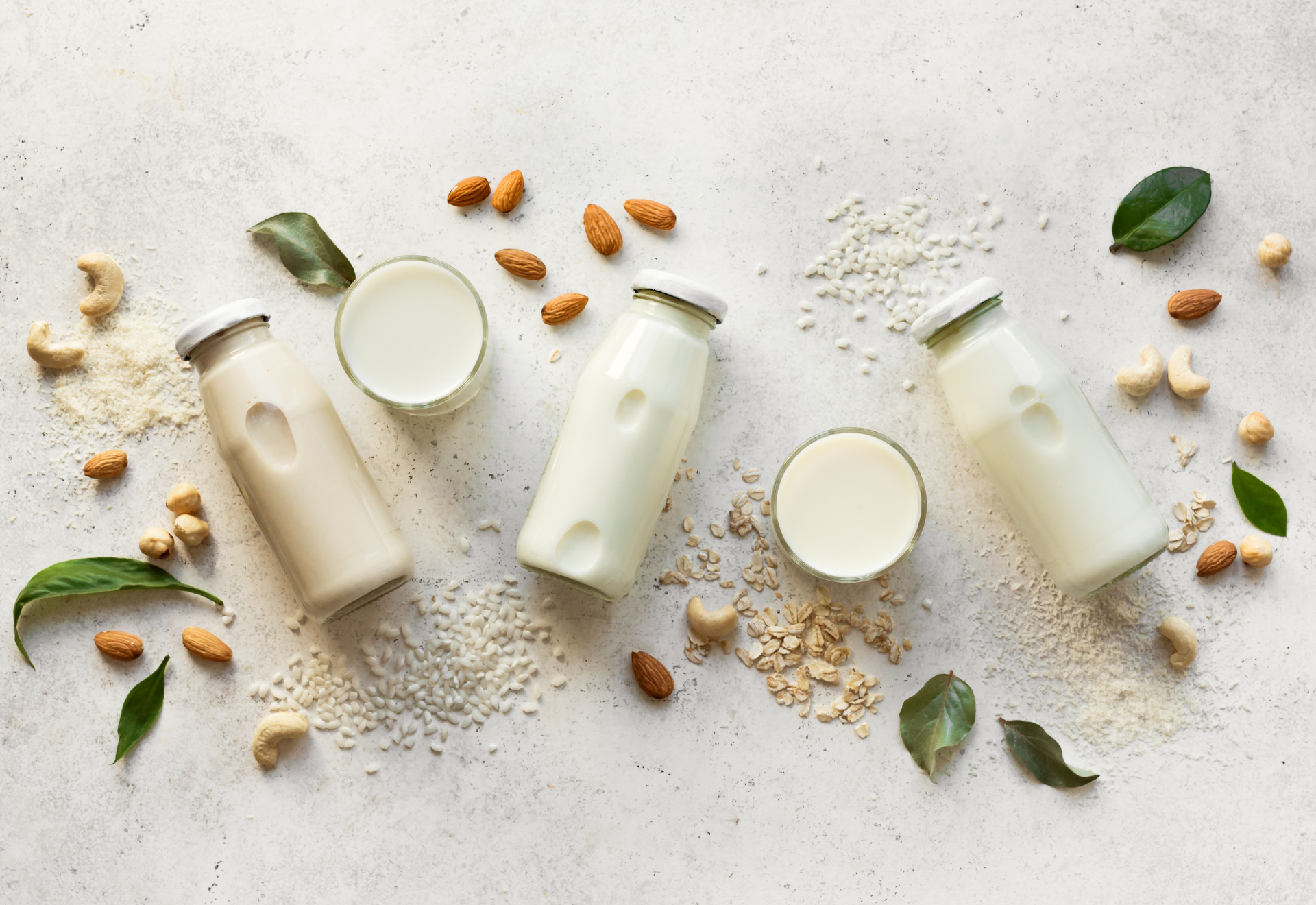 Glasbägare med växtbaserad mjölk på ett bord.
