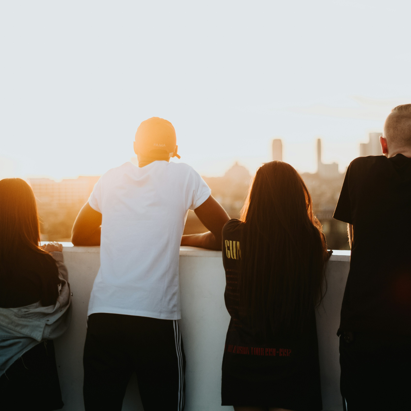 fyra ungdomar blickar ut över en stad från ett tak