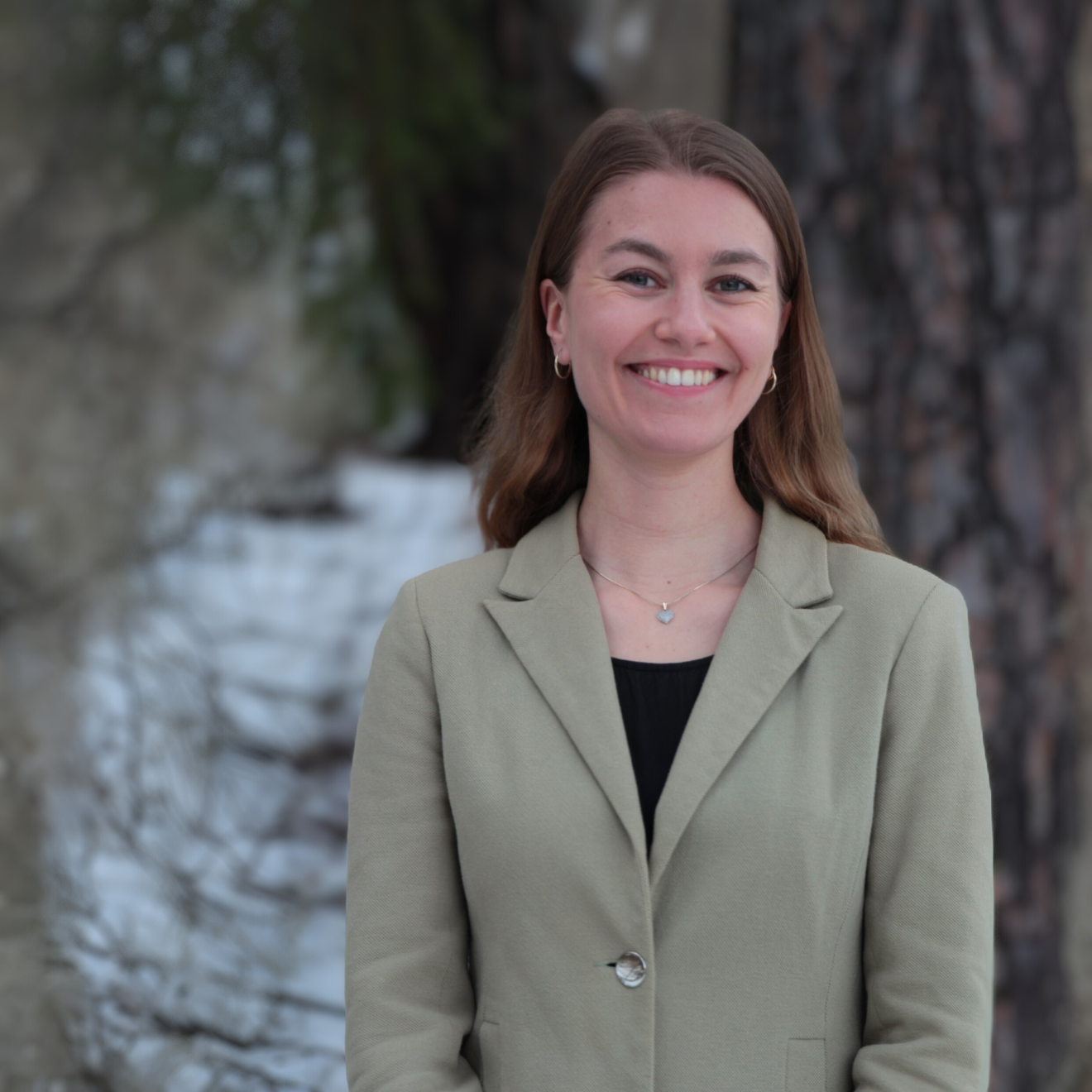 kvinna i kavaj framför ett träd