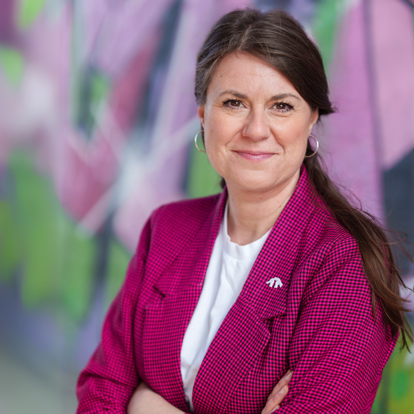 Kvinna i rosa kavaj framför grafittivägg