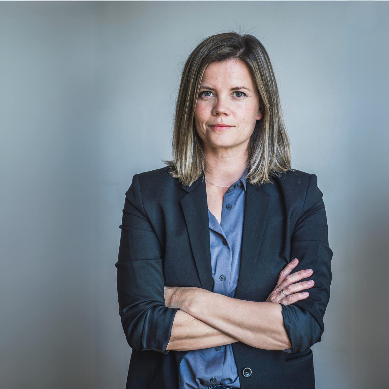 Kvinna i kostym med armarna i kors