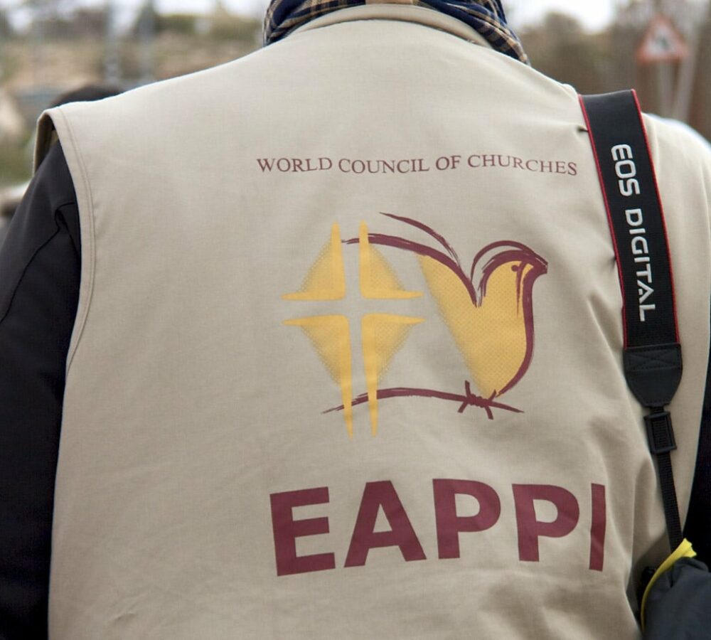 Person med beige väst med texten EAPPI