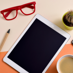 Bild på en iPad, glasögon, penna och kaktus.