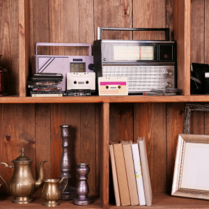 En hylla med kasettband, böcker, ljusstakar och radioapparater.