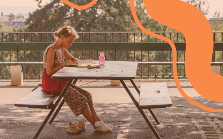 Tjej som sitter ute vid en bänk och pluggar