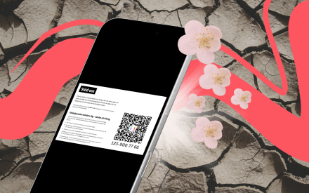 Telefon med Swish logga på. I bakgrunden sprucken torr mark, blommor och ljus bakom telefonen.