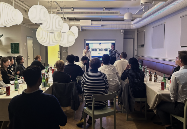 Bild på människors ryggar som sitter och tittar på en workshop.