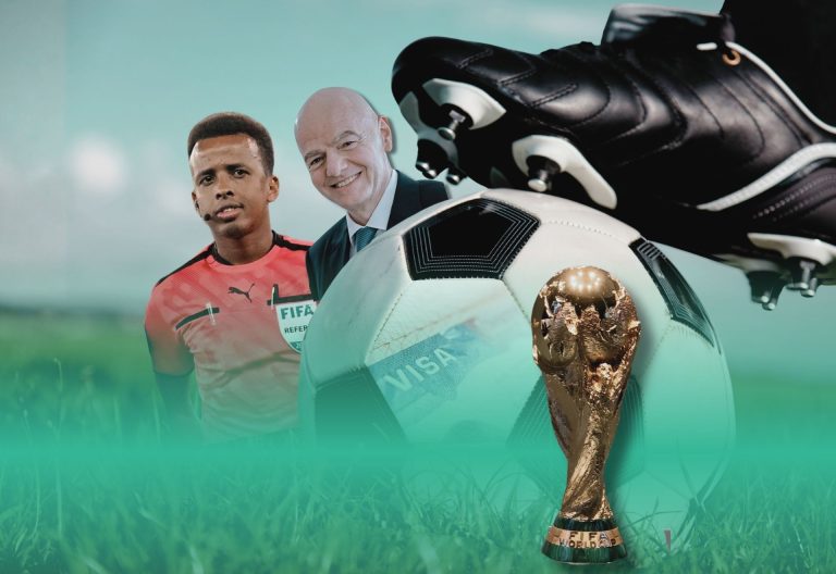 Två män inklippta bakom en fotbollsko på en fotboll och en vm byst